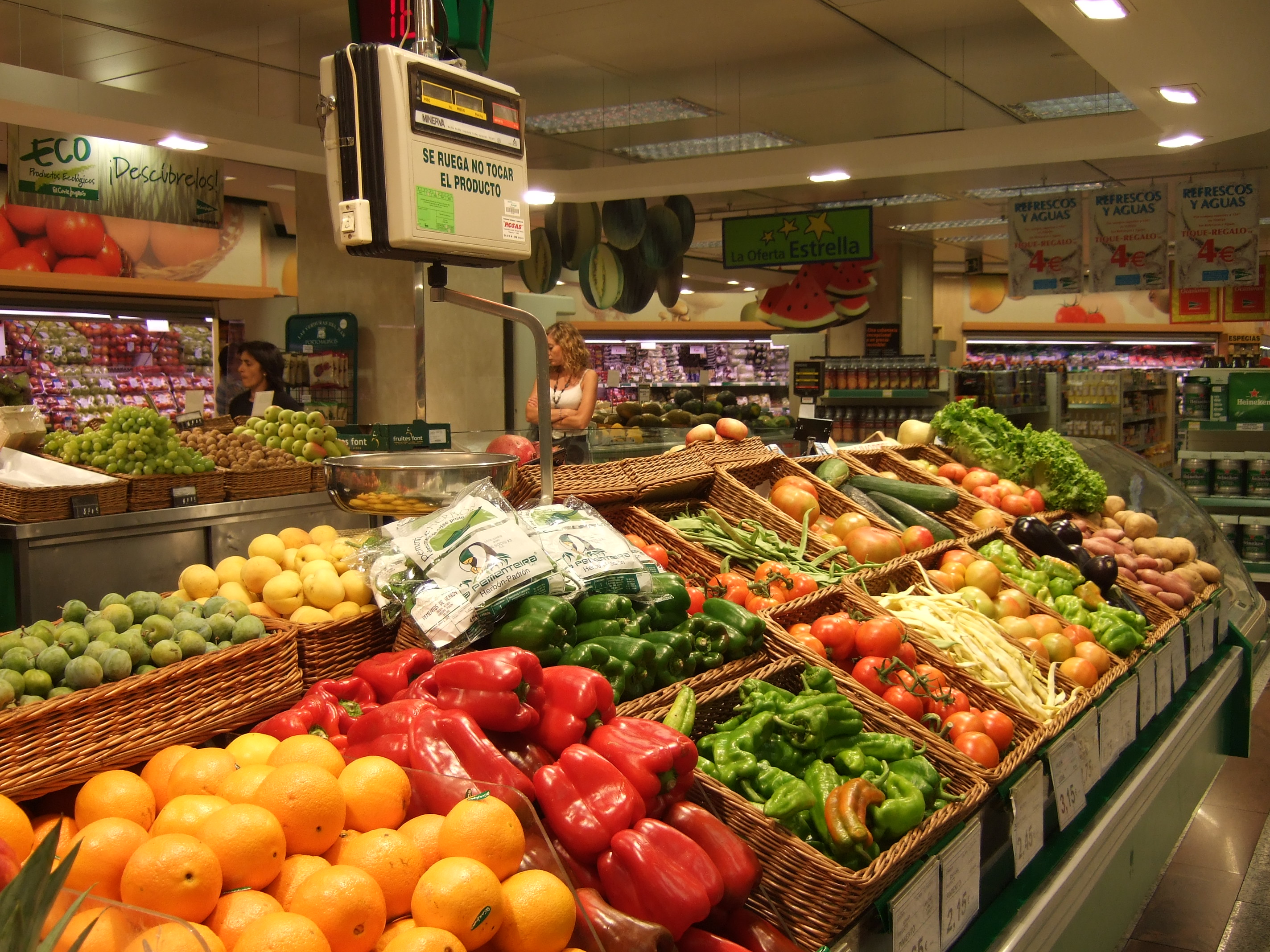 Bancas de frutas e legumes organizadas em um supermercado com grande variedade de produtos frescos